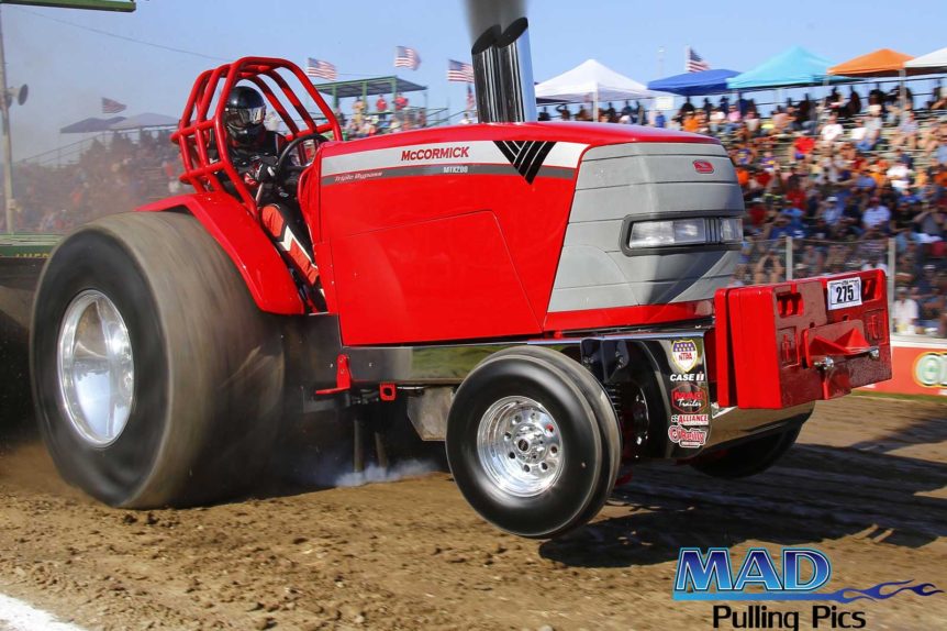 A red tractor driving on dirt.