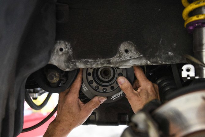 A man is working on a car's suspension during the online race industry week.